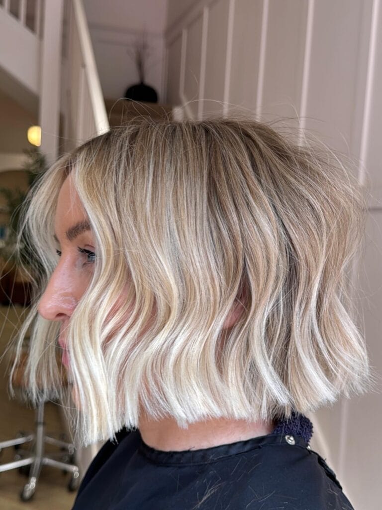 Chin length blonde bob with soft waves and subtle layers.