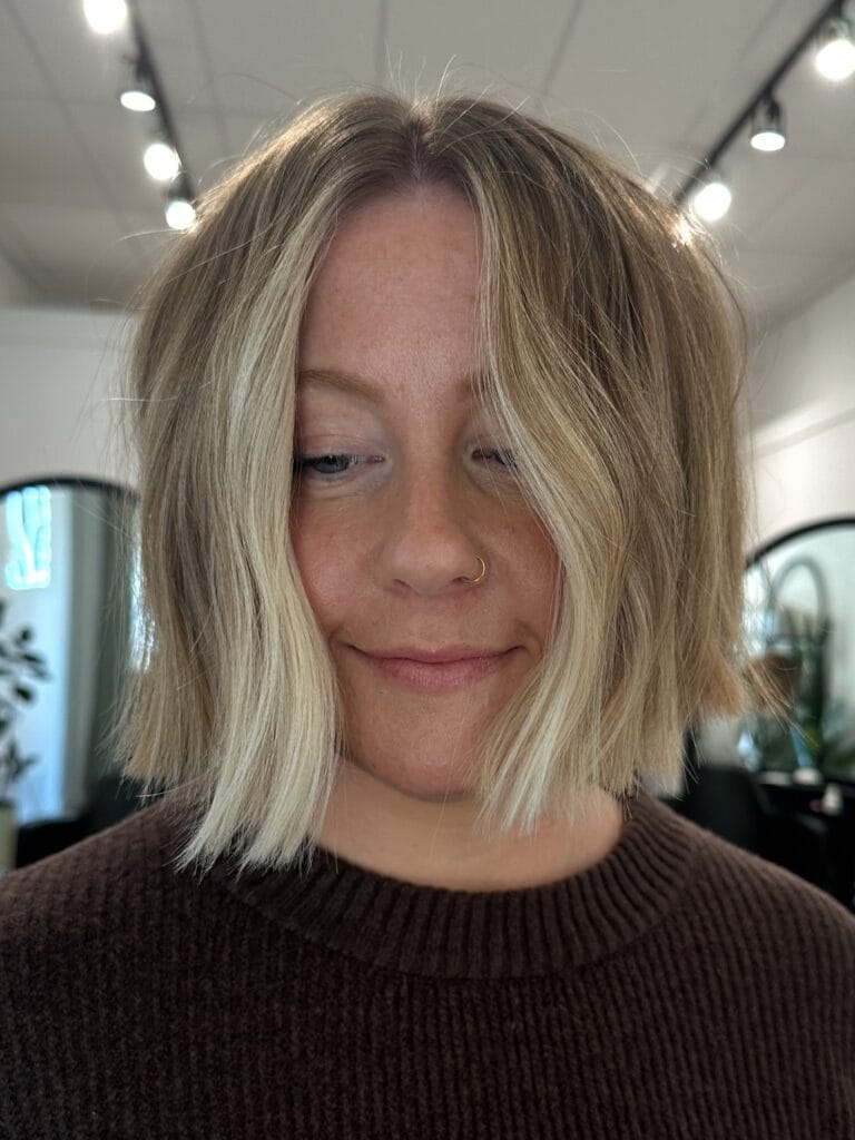 Blonde layered bob with a center part and smooth finish.