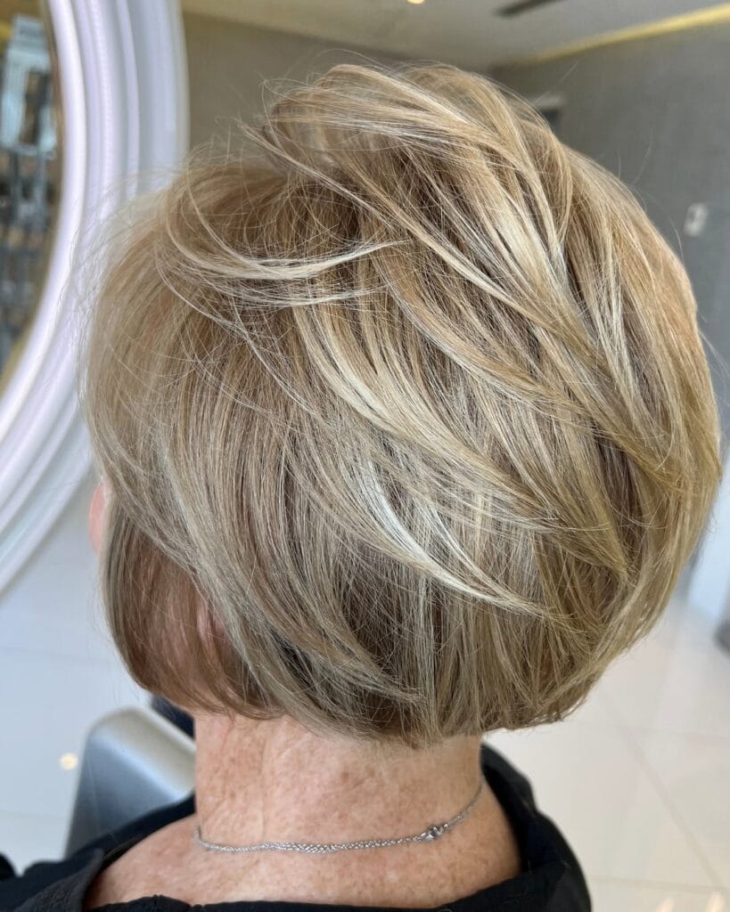 A stacked layered messy bob with soft lift and blended blonde tones.