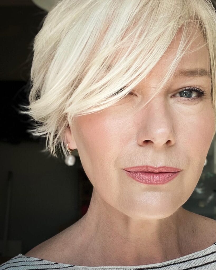 A side swept blonde bob with feathered layers and soft airy texture.
