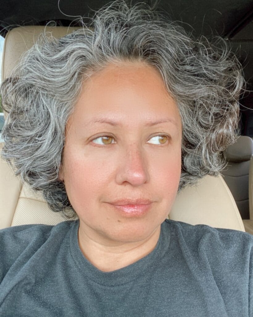 A natural gray curly messy bob with soft volume and textured shape.