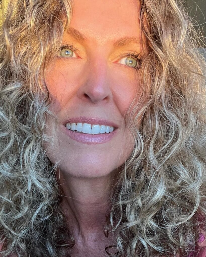 Long blonde curly hair with loose natural texture.