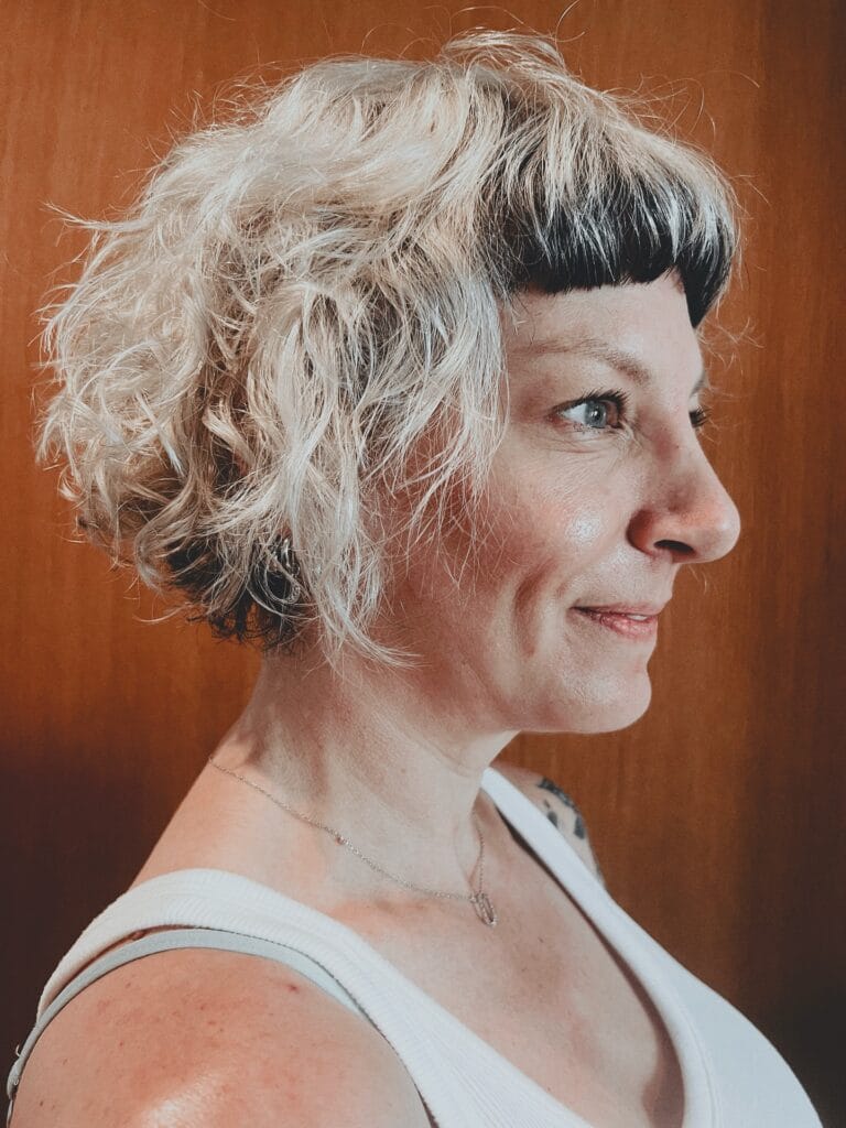 Curly shaggy bob haircut with layered volume and soft blonde color.