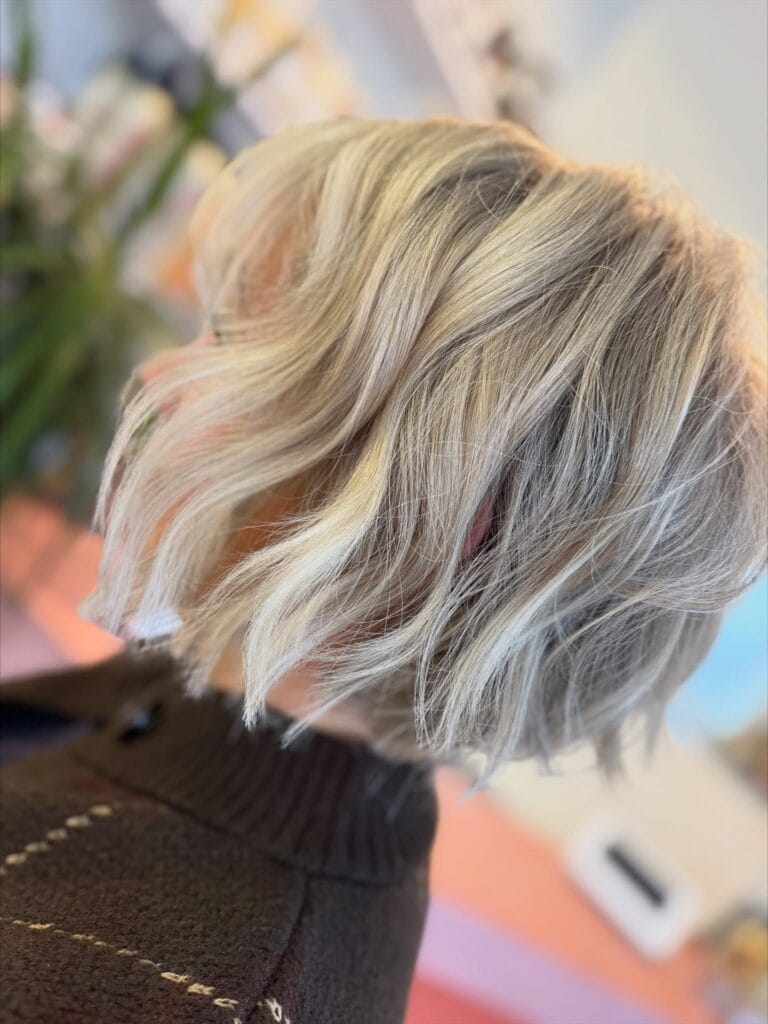 Tousled blonde shaggy bob haircut with soft waves and layered texture.