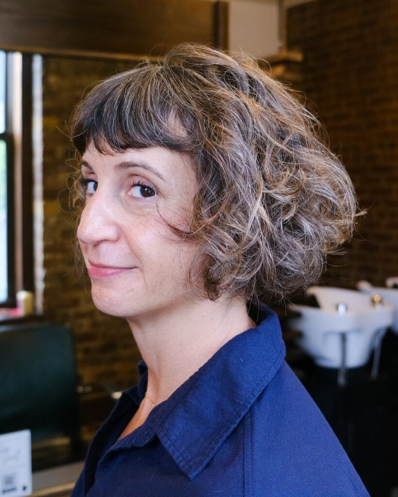Curly shaggy bob haircut with layered shape and soft volume.