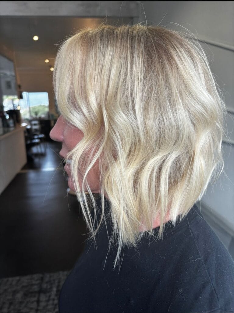 Blonde shaggy bob haircut with soft waves and textured layered ends.