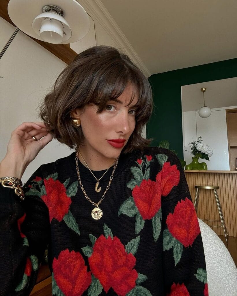 Brunette shaggy bob haircut with soft layers and full fringe.