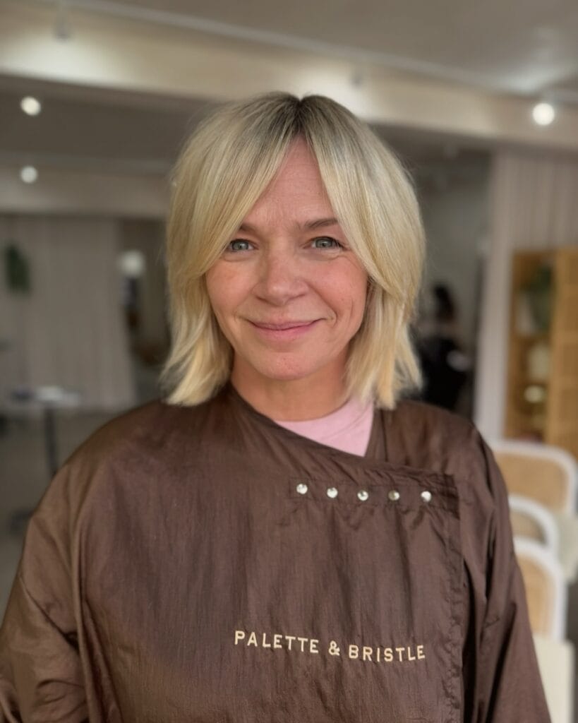 Blonde shaggy bob haircut with curtain layers and soft texture.