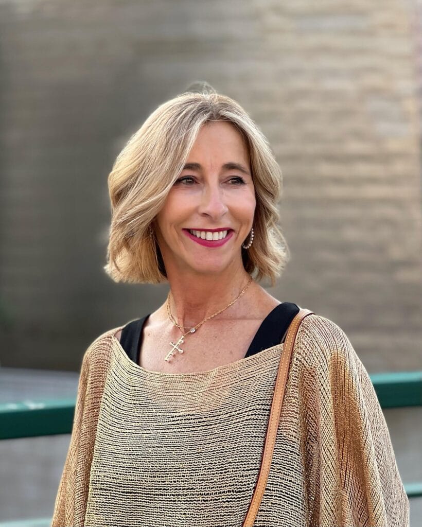 Shoulder length shaggy bob haircut with soft layers and warm blonde tone.