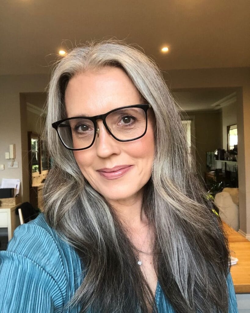 Long silver layered hairstyle with face framing layers and soft movement.