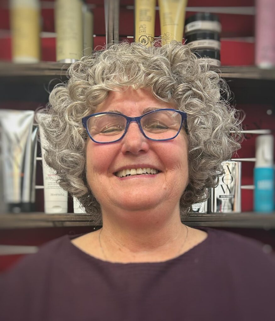 A smiling woman with a chin-length, rounded bob consisting of tight gray curls.
