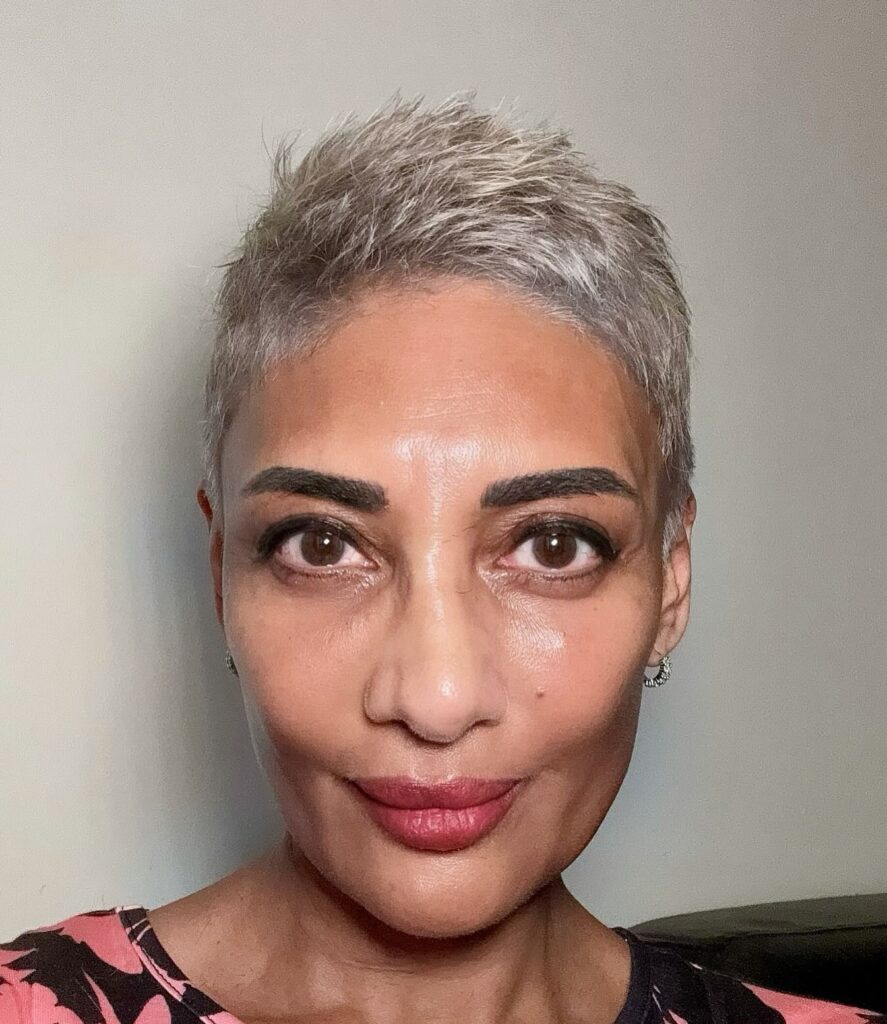 A woman over 50 with a short, spiky salt-and-pepper pixie cut featuring textured layers on top and closely cropped sides.