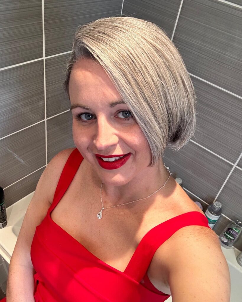 A woman with a straight, chin-length, asymmetrical bob in a cool shade of gray.