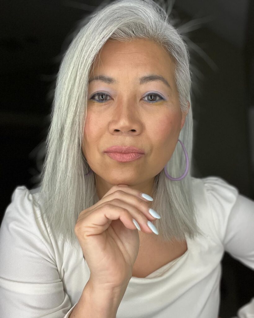 A woman with shoulder-length straight hair in a bright, icy white shade tucked behind one ear.