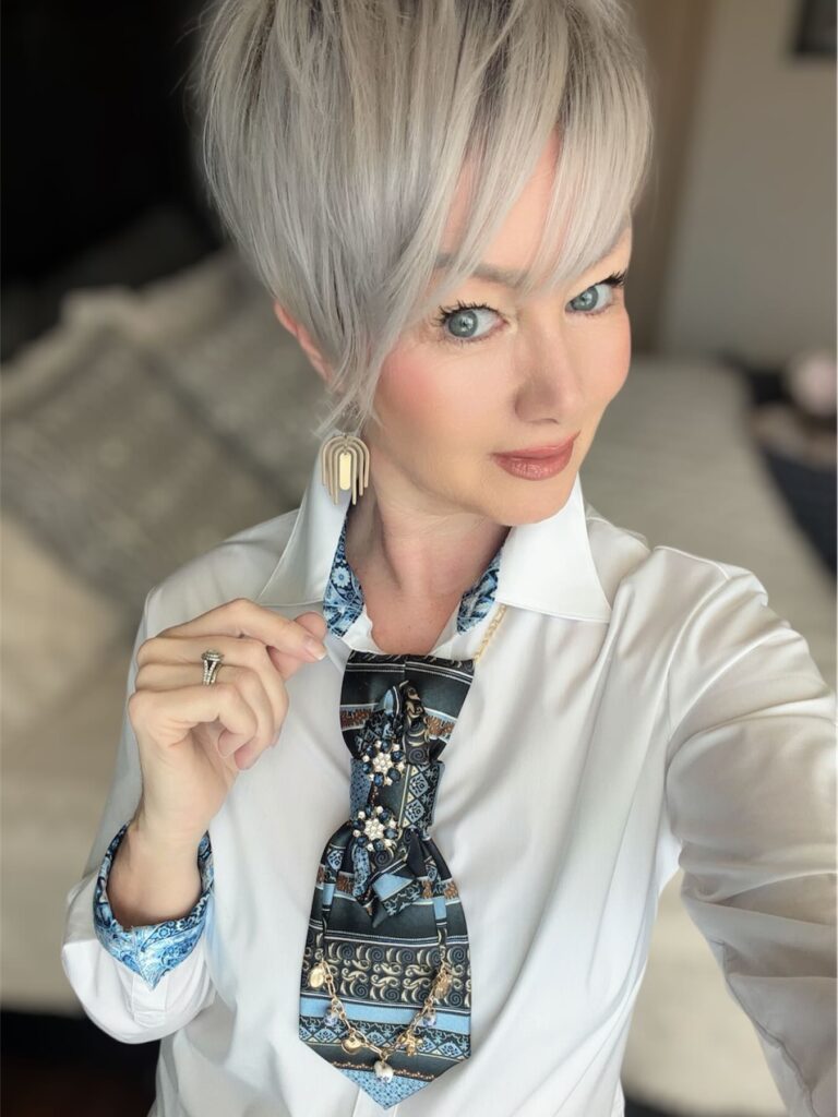 A woman with an edgy ash silver pixie cut featuring a long wispy fringe and significant volume at the crown.