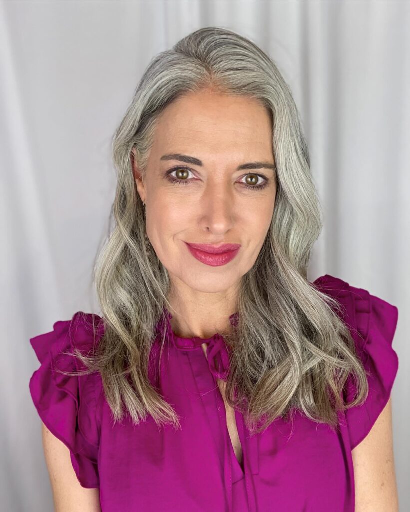A woman with long, wavy, gray hair falling past her shoulders with a soft side part.