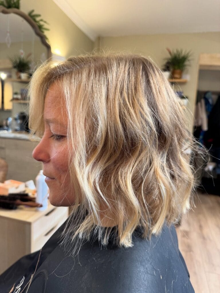 Shoulder length blonde hair with textured beachy waves and light layers.