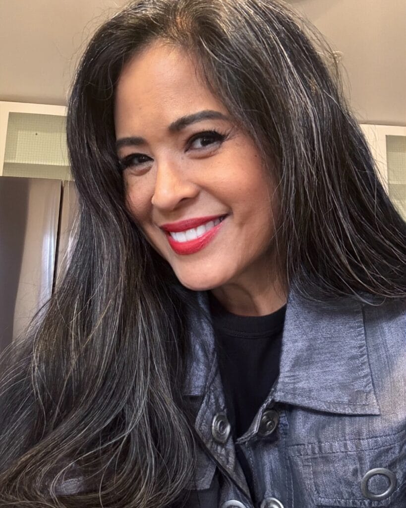 Long dark hair styled with smooth soft waves and subtle volume.