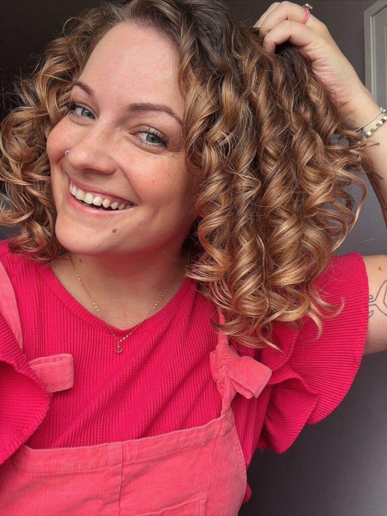 Medium length curly hairstyle with caramel highlights and lively ringlet curls.