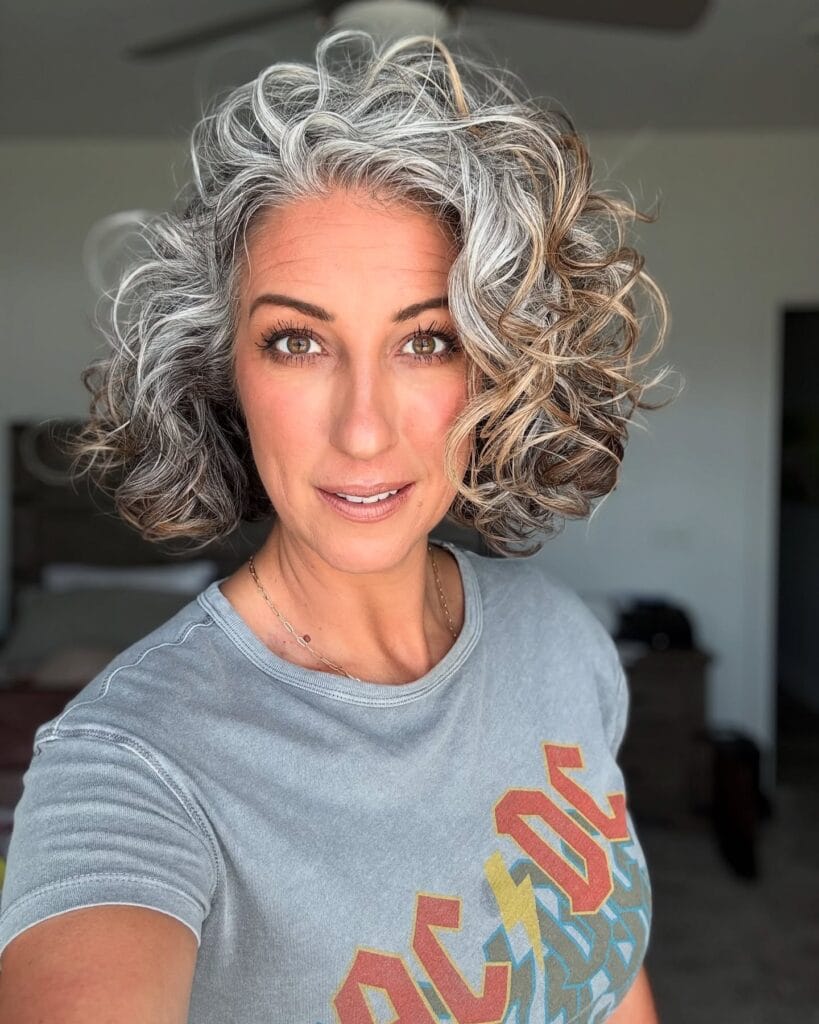 Short silver curly bob with bouncy layers and natural volume.