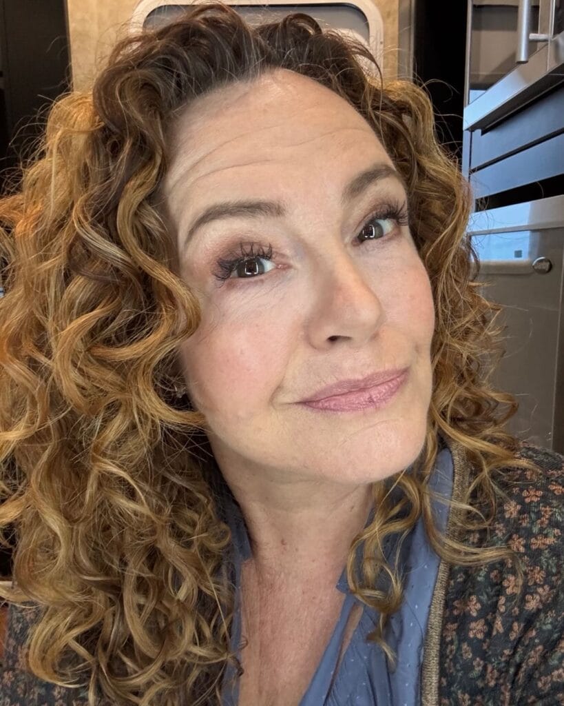 Medium length copper curly hair with defined natural curls and layered shape.