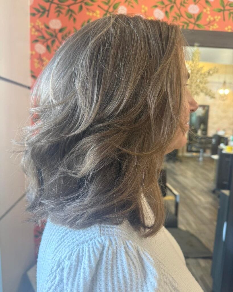 Medium length brunette layered hairstyle with soft movement and lightly textured ends.