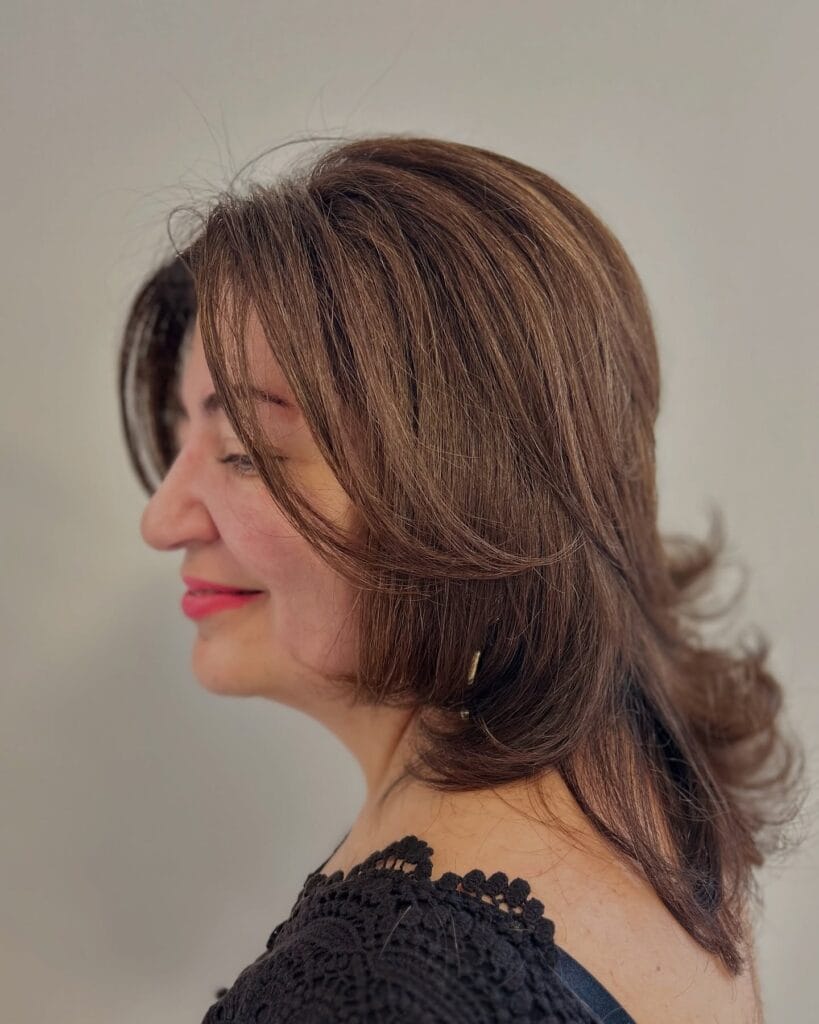 Medium length layered brunette hair with softly flicked ends and natural movement.