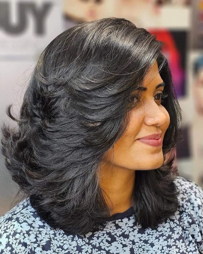 Medium to long dark layered hair with a full side swept shape and volume.
