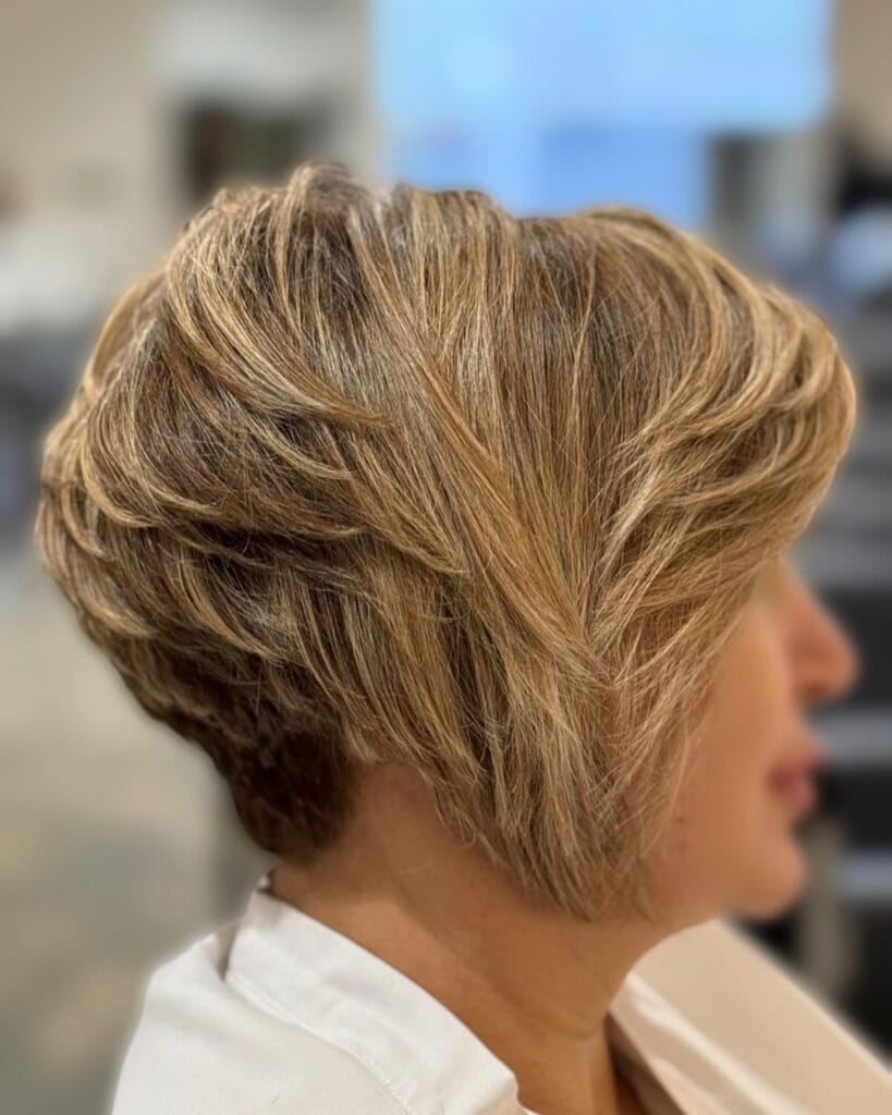 Short blonde layered hairstyle with textured layers and volume at the crown.