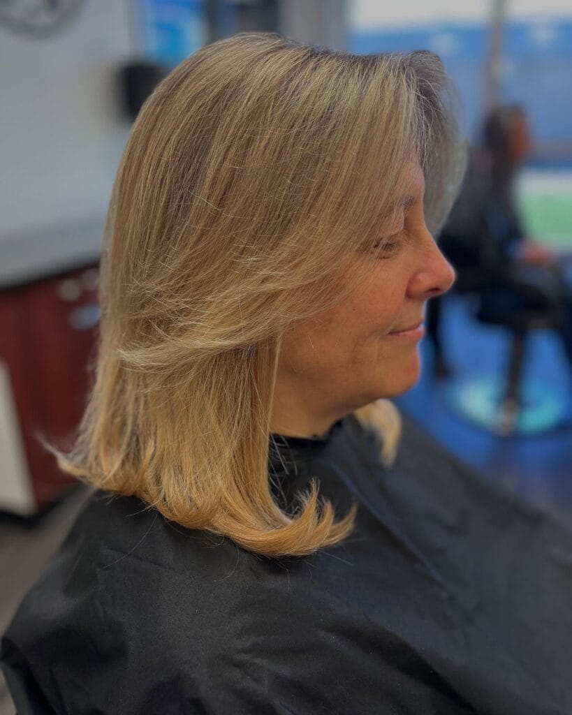 Shoulder length blonde hair with soft feathered layers styled outward for a light and airy look.