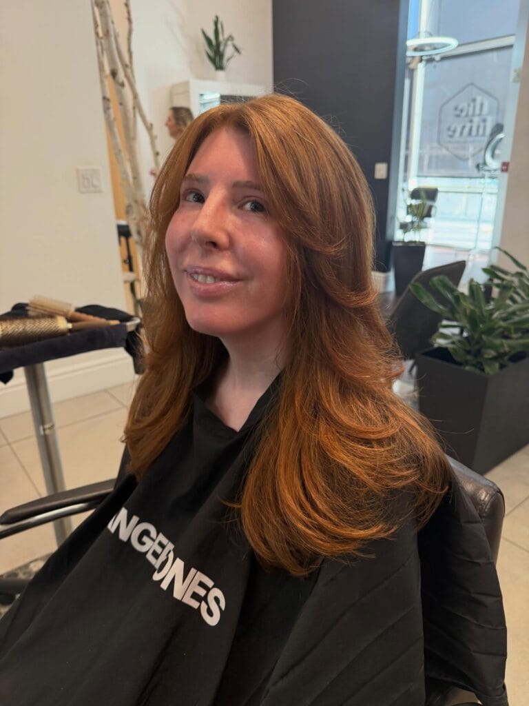 Medium length auburn layered hair with soft curls and a bouncy finish.