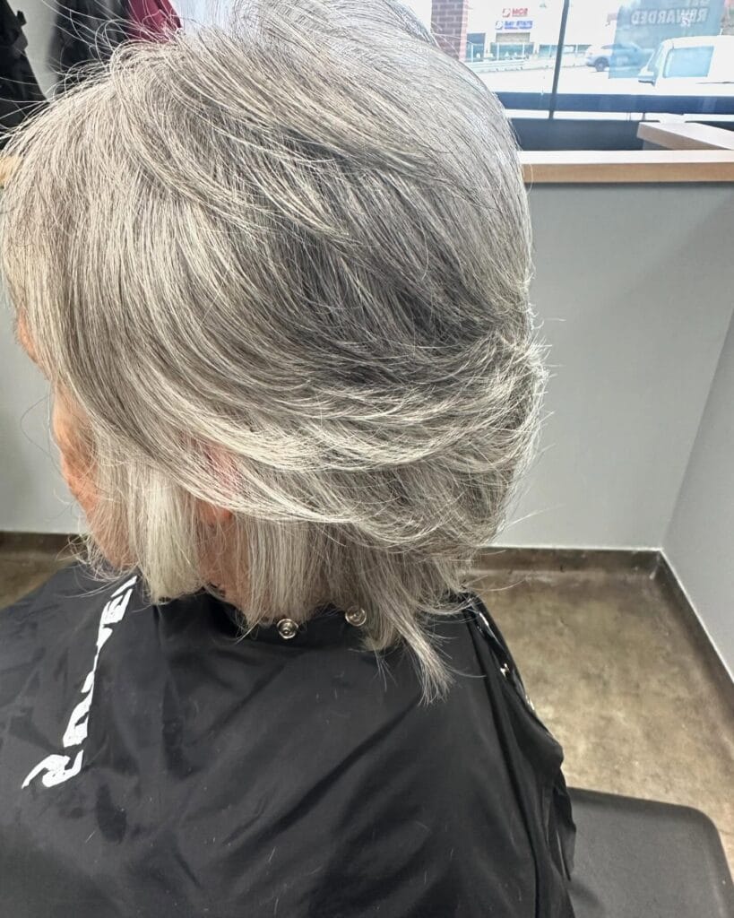 Short gray layered hairstyle with soft volume and a rounded shape at the back.