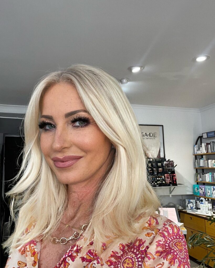 A woman with shoulder-length bright platinum blonde hair styled with smooth sweeping layers and a middle part.