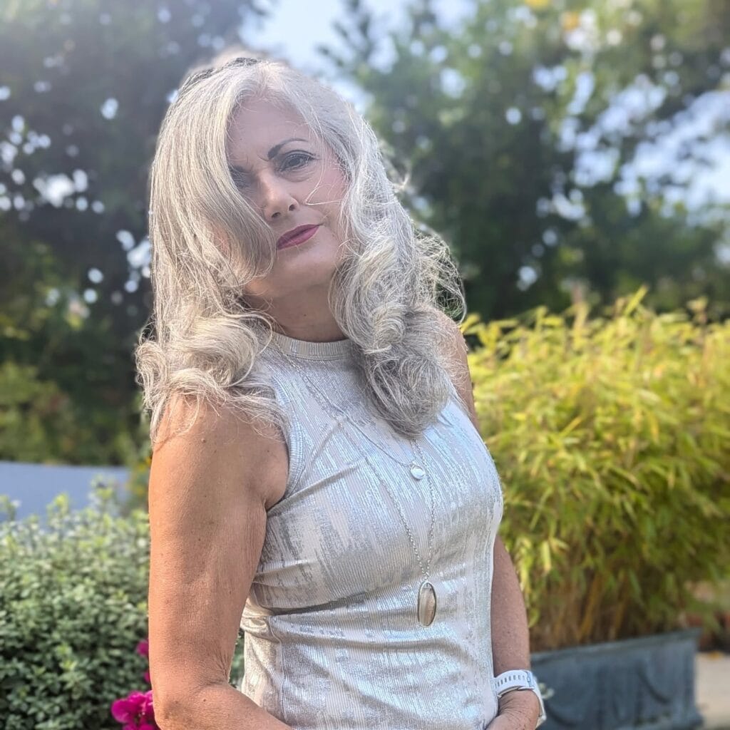 Long gray hair styled in glamorous side parted waves.