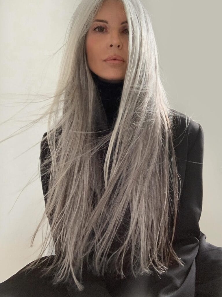 Long natural gray hair with soft waves and a middle part.