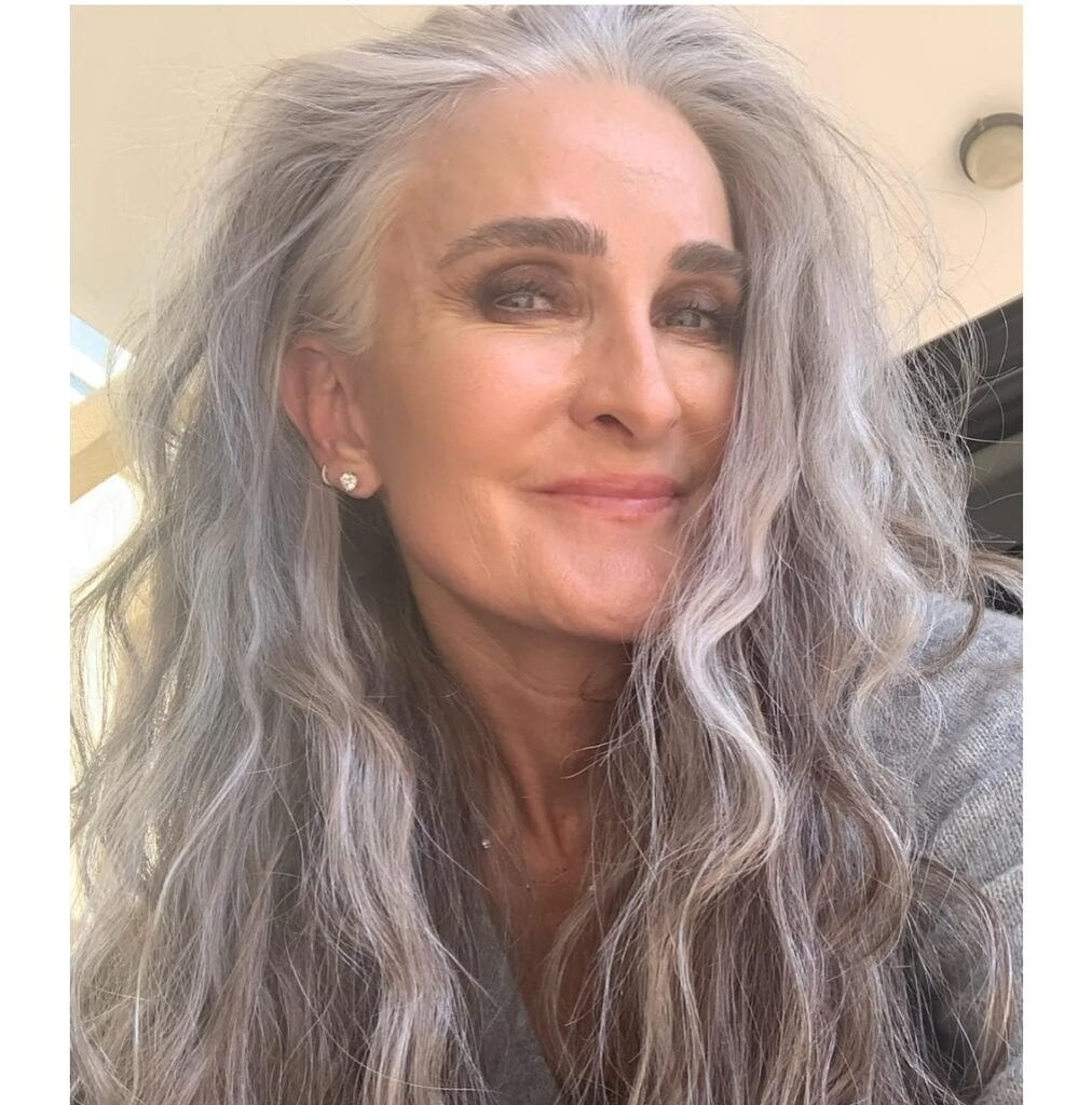 Long salt and pepper gray hair with soft natural waves.