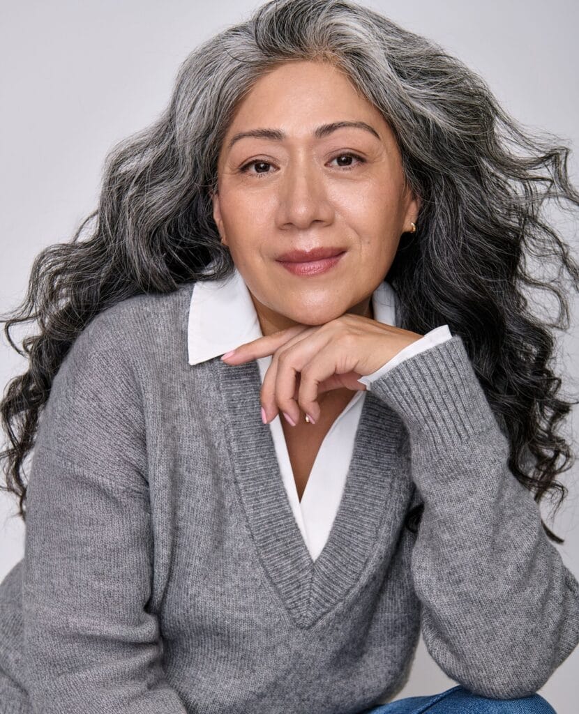 Long gray hair styled with soft natural waves.
