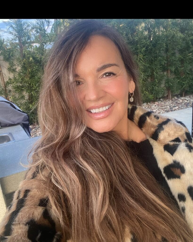 A woman with long honey brown hair styled in loose beach waves.