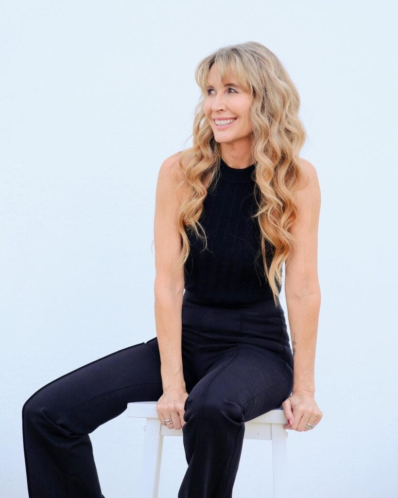 A woman with long blonde hair styled in loose beachy waves.