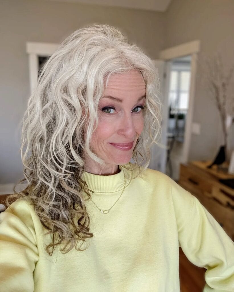 A woman with long silver gray hair styled in natural loose curls.