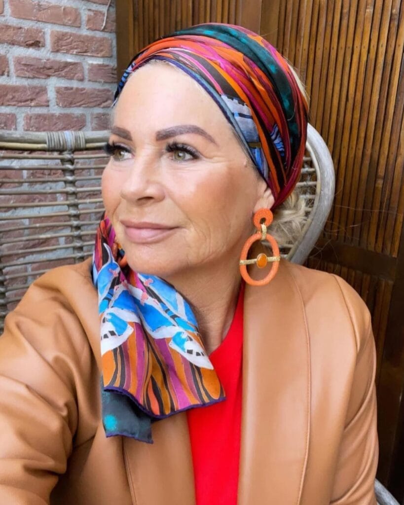Low ponytail hairstyle wrapped with a colorful patterned silk headscarf.