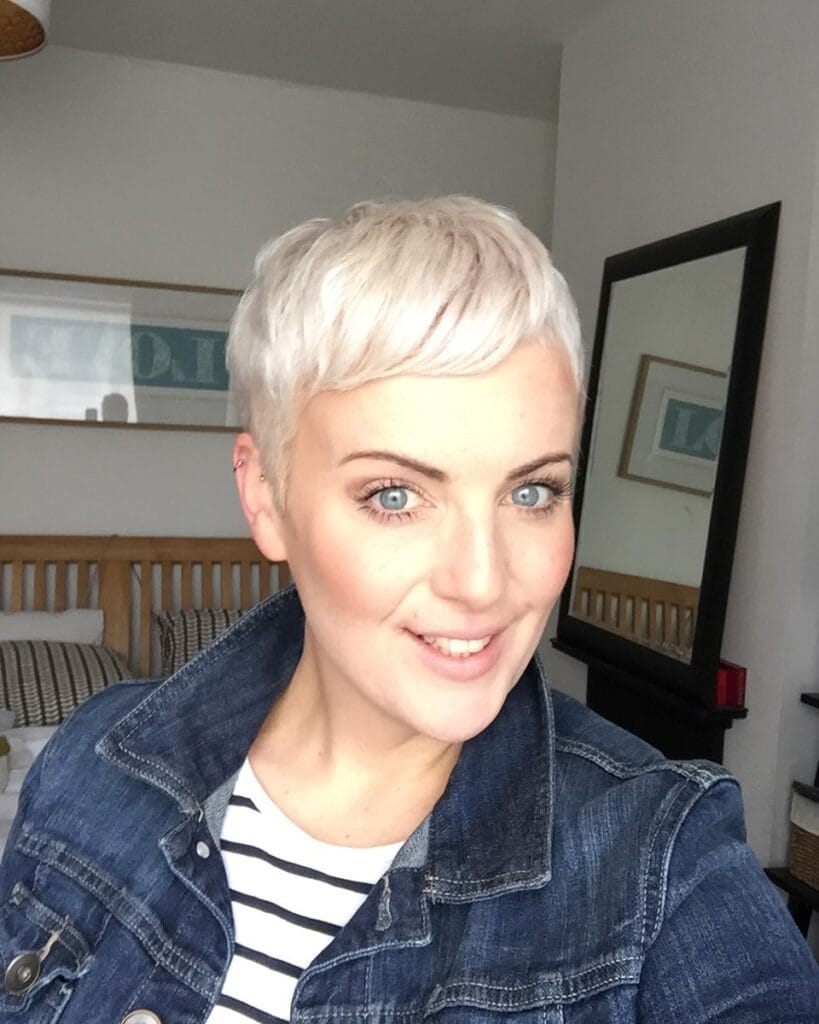 Very short platinum blonde pixie haircut with textured layers and neatly cropped sides.
