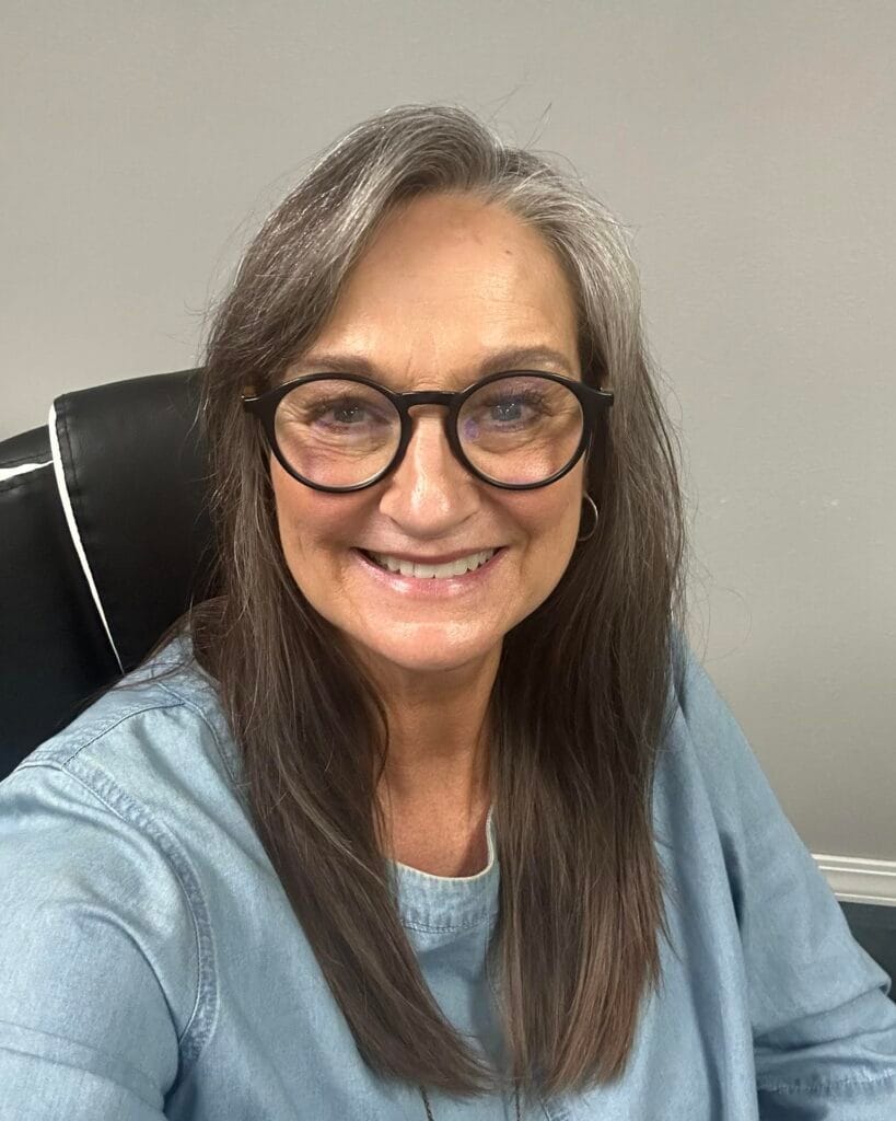 Long straight layered hairstyle with a natural blend of brunette and gray tones.