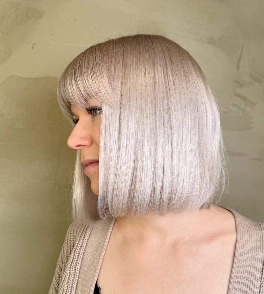 Blunt platinum gray bob with full straight fringe and sharp clean edges.