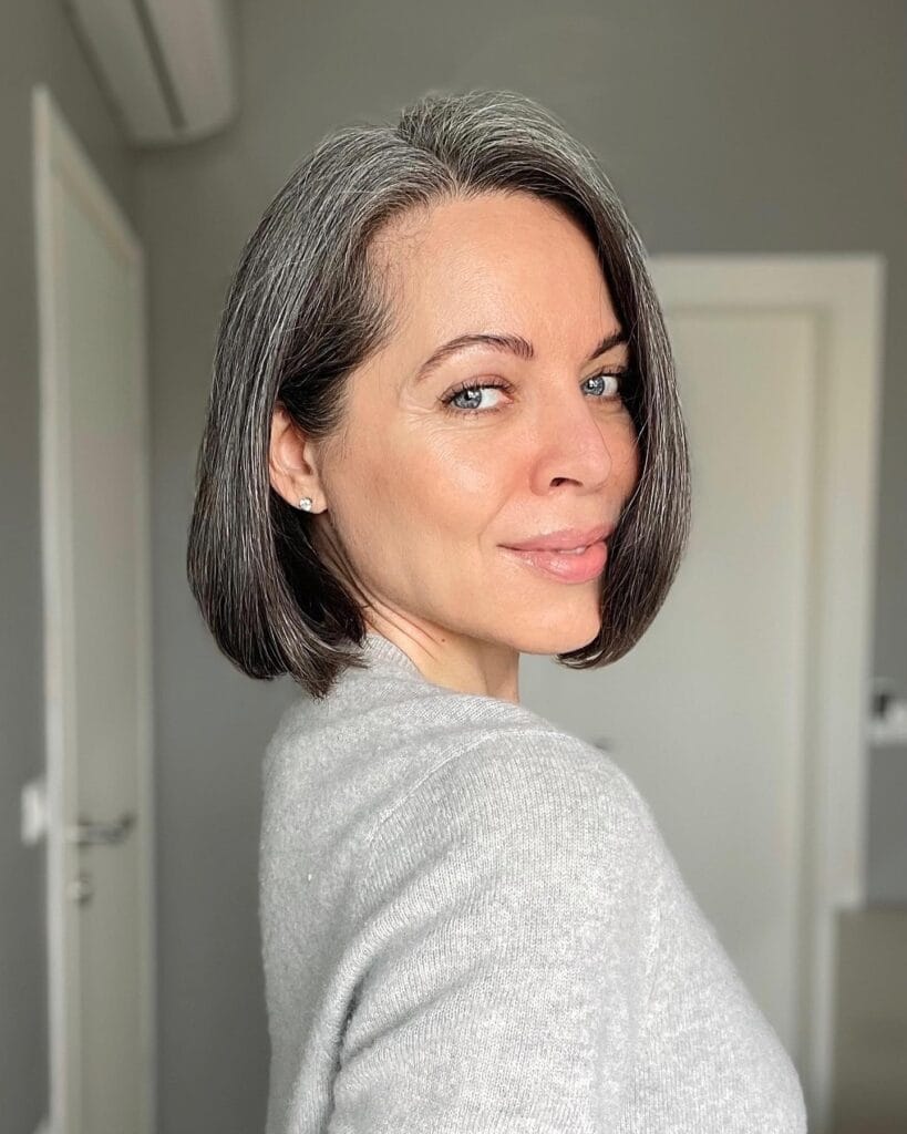 Chin length sleek gray bob with side part and softly curved ends.