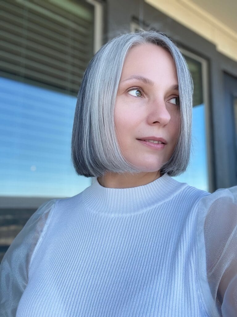 Chin length blunt silver bob with center part and sleek straight finish.