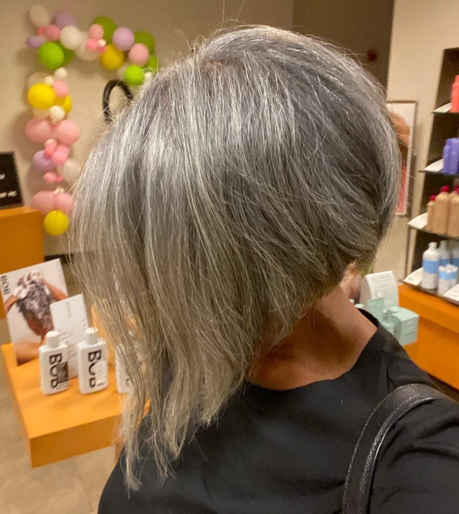 Side swept gray bob with soft layers and natural volume creating a full airy shape.