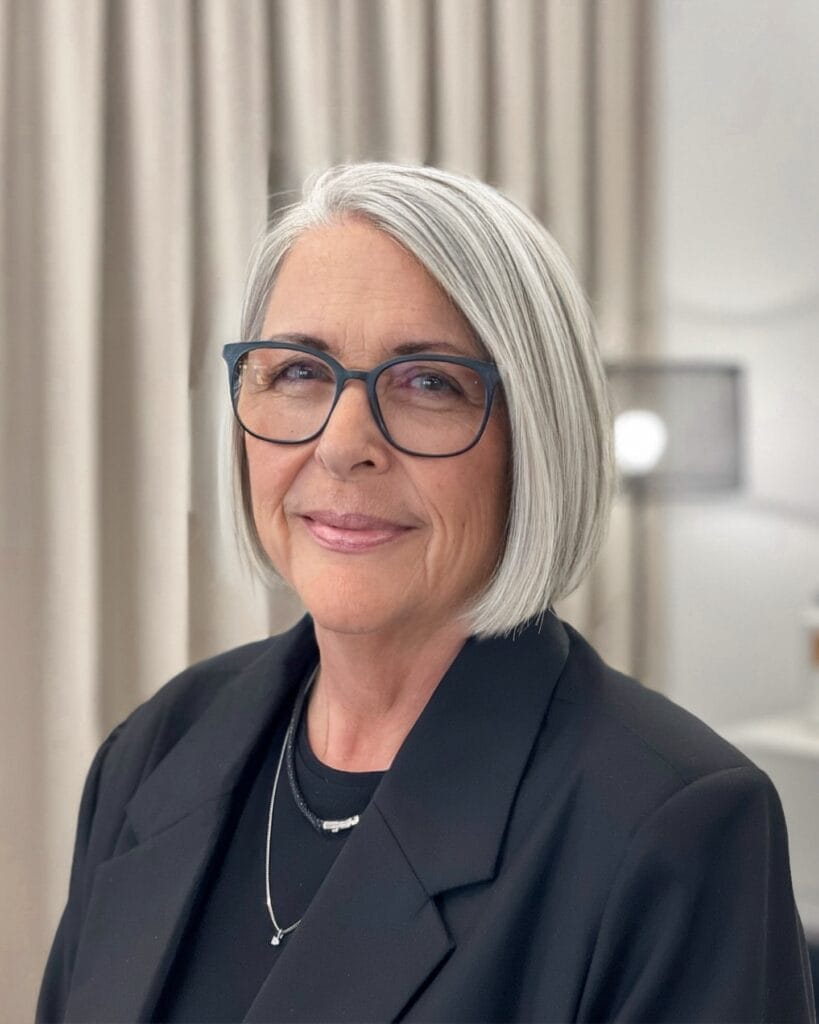 Jaw length straight gray bob with a smooth finish styled neatly with glasses.