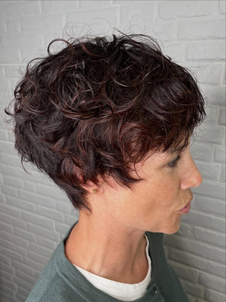 Layered curly pixie with tapered back and soft textured curls.