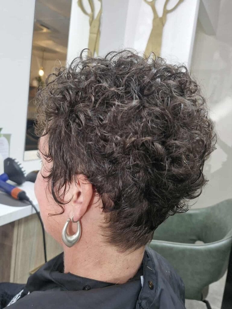 Curly pixie with tapered back and textured volume at the crown.